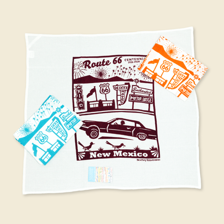 Route 66 kitchen towels with illustrated cars and roadside buildings in burgundy, turquoise, and orange. 